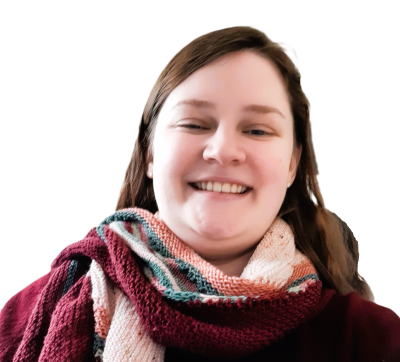 A woman smiling while standing in front of white wall.