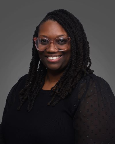 A woman smiling while standing in front of a dark gray background